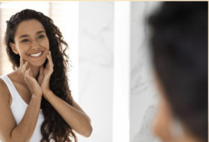 Woman smiling at herself in the mirror, embracing self-love