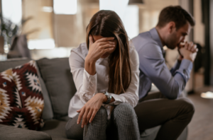 Couple sitting on a sofa facing opposite to each other with emotional distance, struggling with codependent relationship dynamics